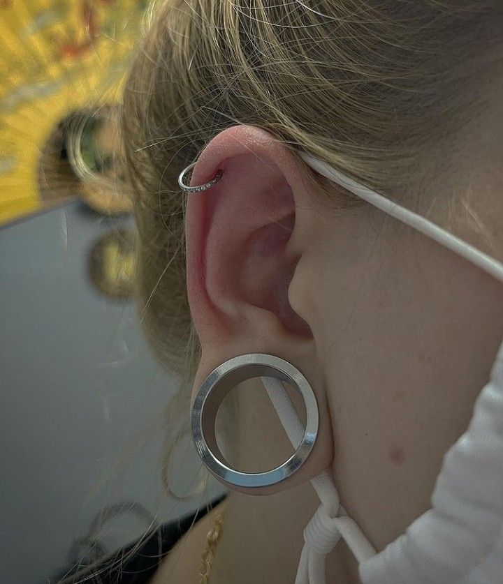 a close up of a person wearing some kind of earring with a ring on it