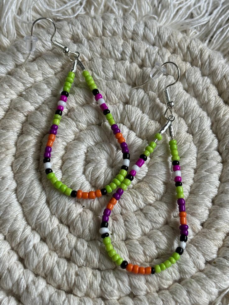 two colorful beaded earrings sitting on top of a white rug