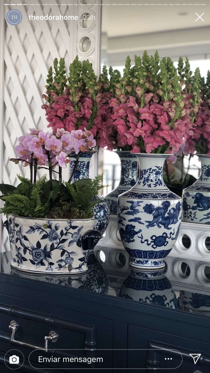 several vases with flowers in them sitting on a table next to a mirror,