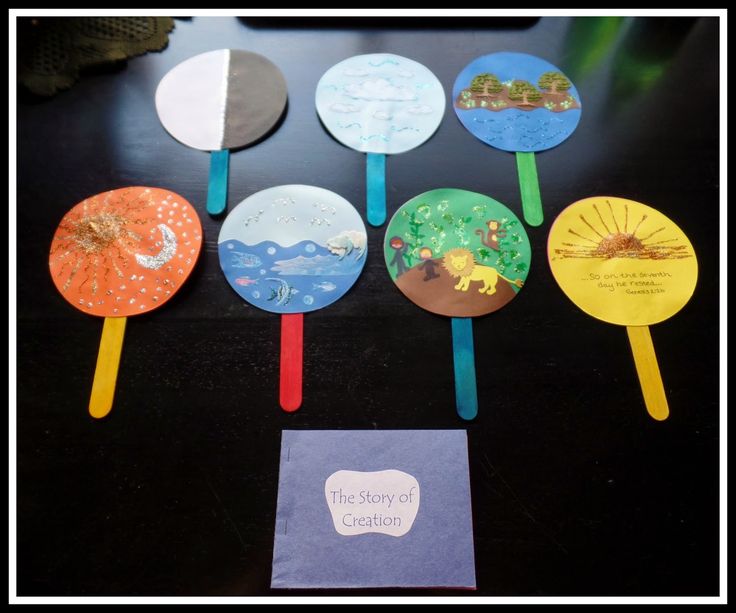 there are many different colored plastic spoons on the black table and one has a book in front of it