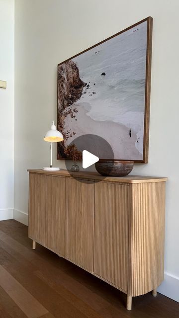 a wooden cabinet with a painting on the wall