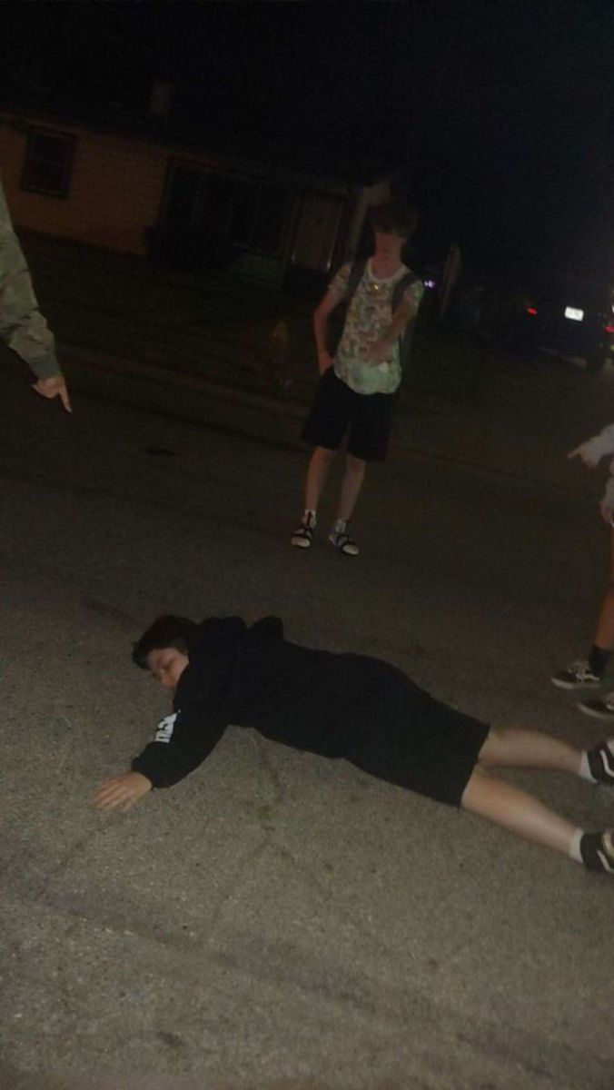 a person laying on the ground with a skateboard in their hand and another person standing behind them