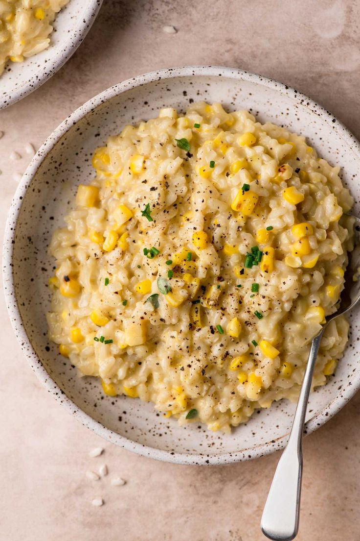 two white bowls filled with macaroni and cheese on top of a beige table