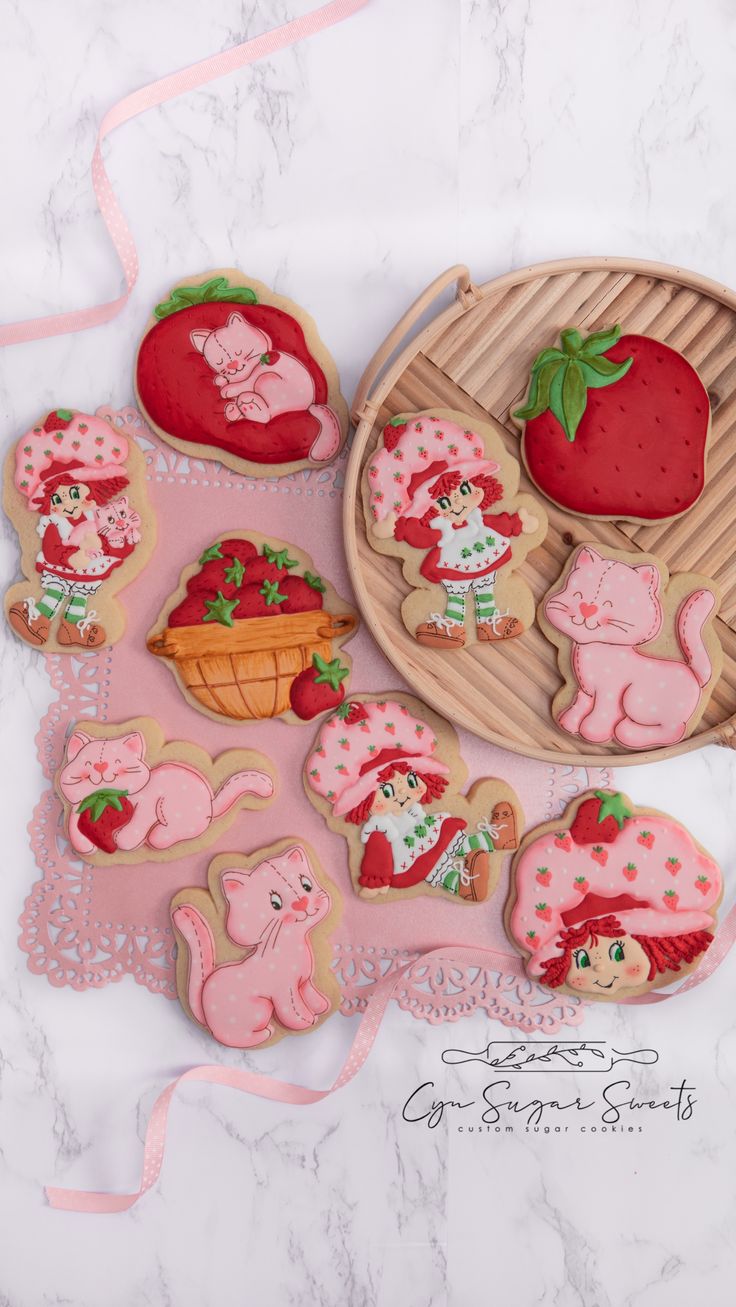 several decorated cookies are sitting on a table next to a plate with strawberries and pigs