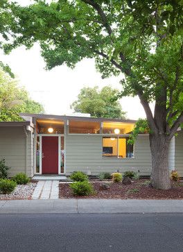 a house with a red door and trees in the front yard on a sunny day