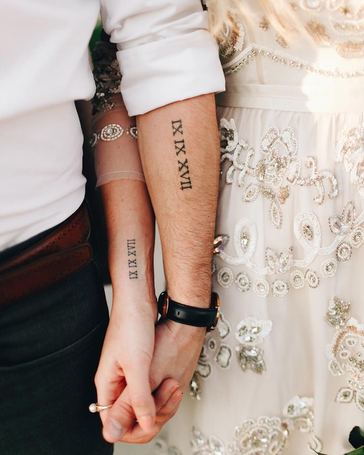 two people holding hands with tattoos on their arms