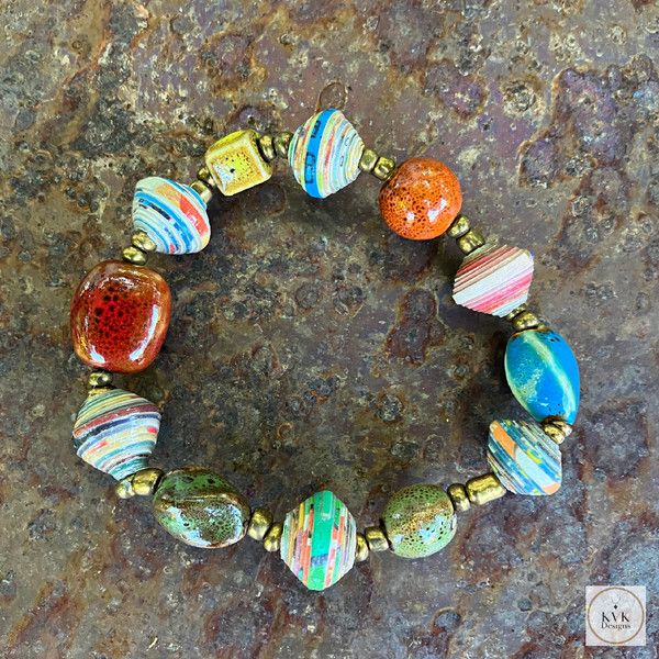 a close up of a bracelet made out of glass beads on a stone surface,