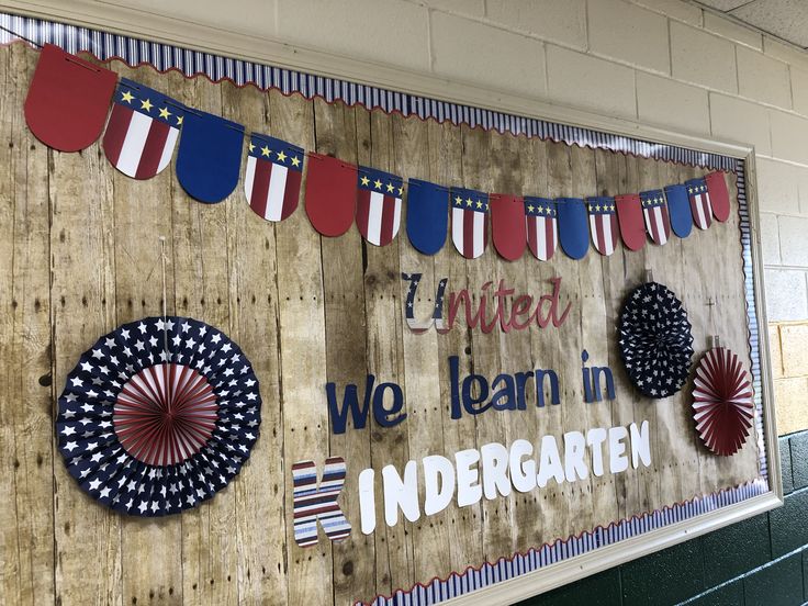 a bulletin board with american flags and bunting on it in a school gym room