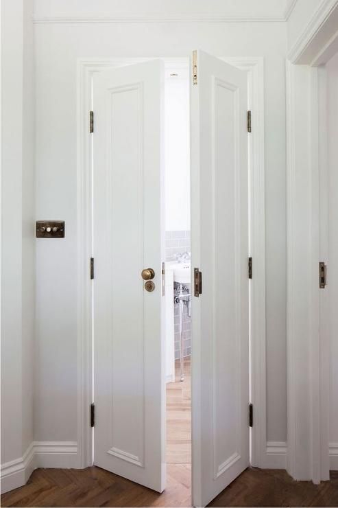 an open door leading to another room with hardwood floors and white walls, in front of a window