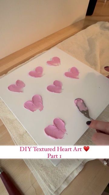 someone is making hearts out of paper on a piece of white paper with pink paint