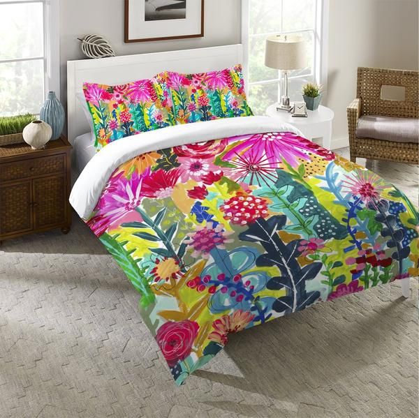 a bed with colorful flowers on it in a room next to a lamp and window