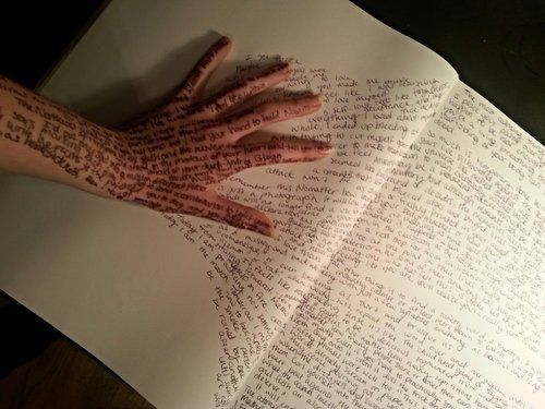 an open book with writing on it and two hands reaching out from the pages that are folded in half