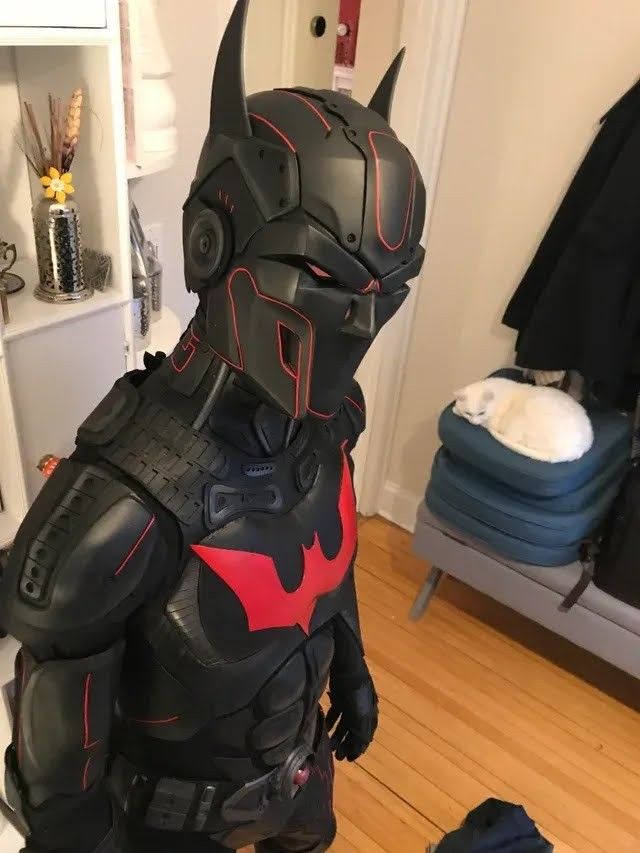 a man in a batman costume standing on a hard wood floor next to a closet