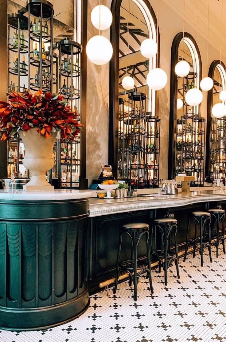 the bar is decorated with black and white tiles, chandeliers, and stools