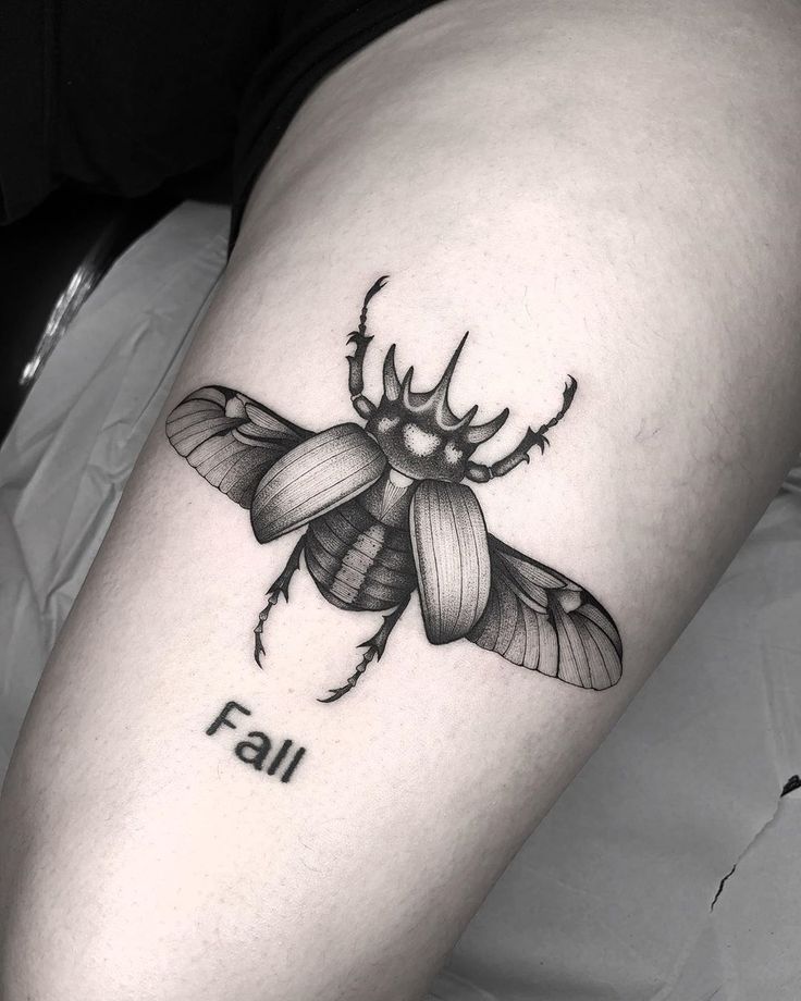 a black and white photo of a tattoo on the leg of a woman's thigh