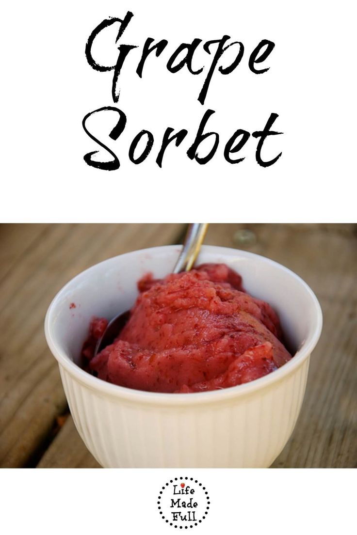 a white bowl filled with red food on top of a wooden table next to a sign that says grape sorbet