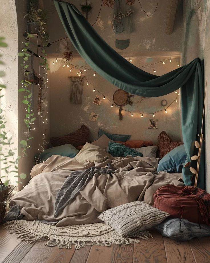 an unmade bed with lots of pillows and blankets on top of it, surrounded by string lights