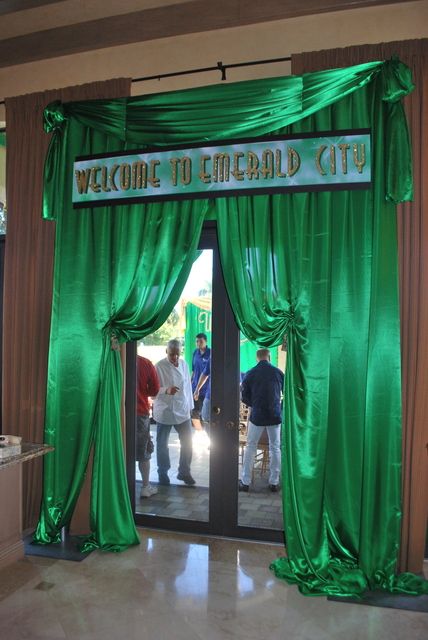 people are standing in front of a green curtained entrance to a building with the words welcome to emerald city on it