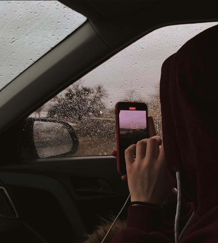 a person in a car taking a photo with their cell phone while it is raining