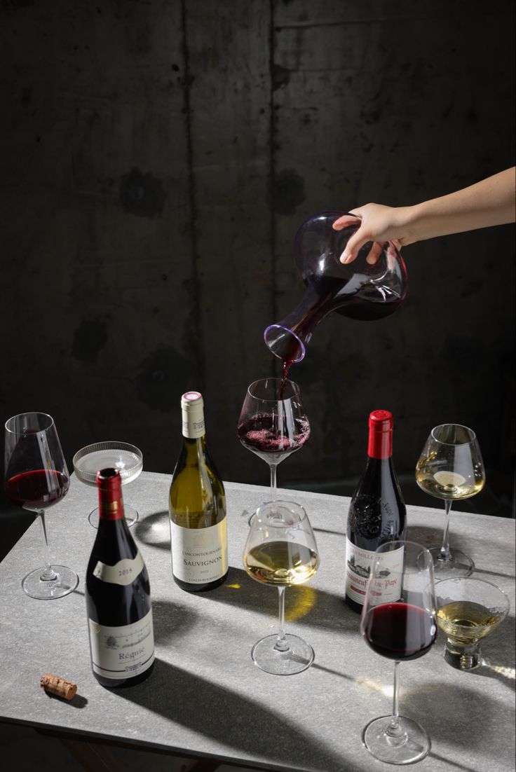 someone pouring wine into several glasses on a table