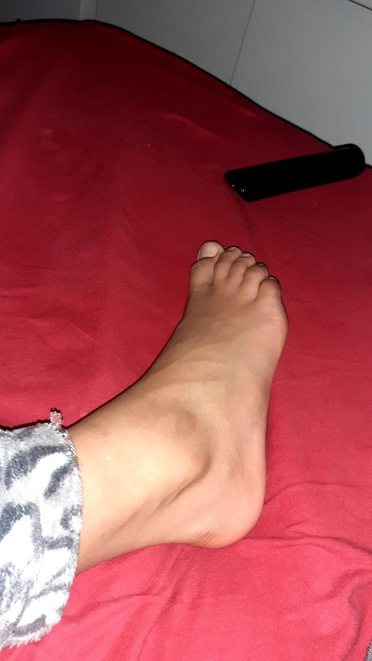 a person's bare feet laying on a red bed