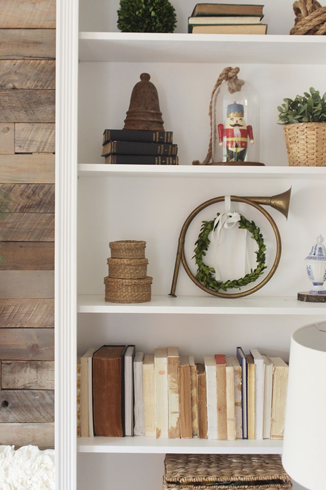 a white book shelf filled with books next to a lamp and other items on top of it