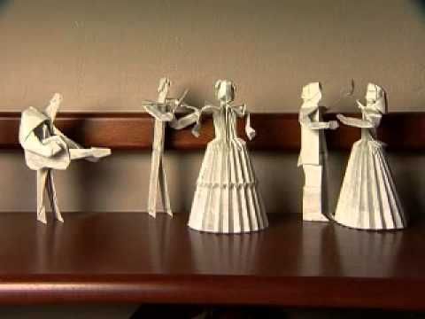 five paper dolls are lined up on a shelf in the shape of people holding hands