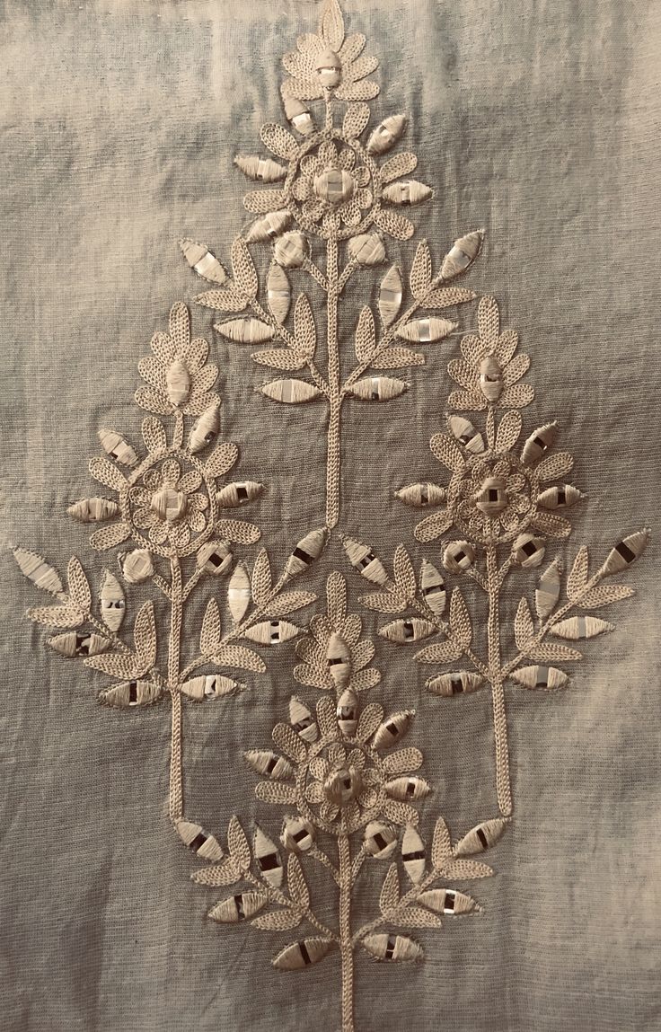 an embroidered piece of cloth with flowers and leaves