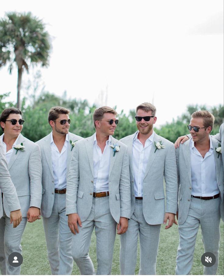 a group of men standing next to each other wearing suits and sunglasses on their heads