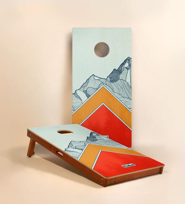 a cornhole game set with mountains painted on it and a hole in the back