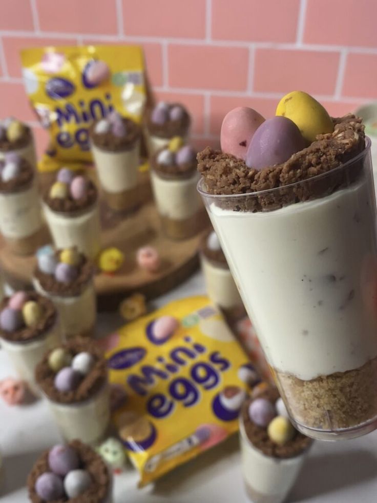 there are many desserts on the table with candy eggs in cups and mini eggs