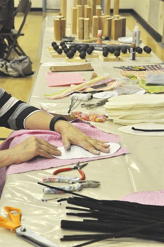 a woman sitting at a table with lots of crafting supplies on top of it