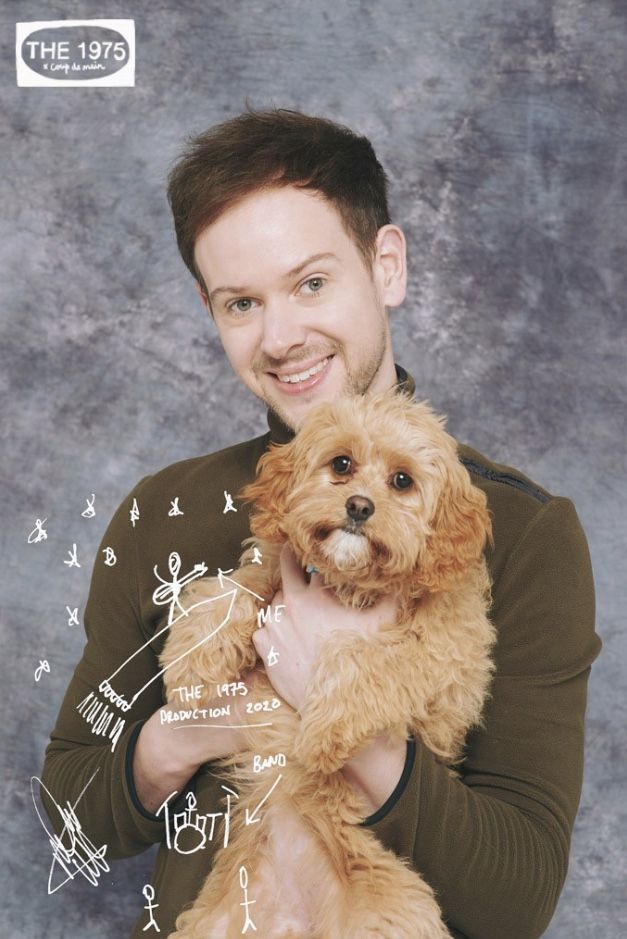 a man holding a brown dog in his arms and writing on the wall behind him