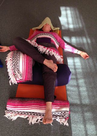 a woman laying on top of a mat in the middle of an office building with her legs crossed