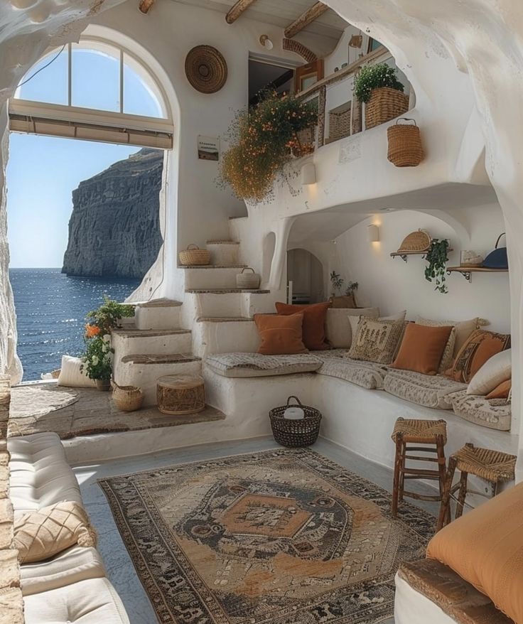 a living room filled with lots of furniture next to an ocean side building on top of a cliff