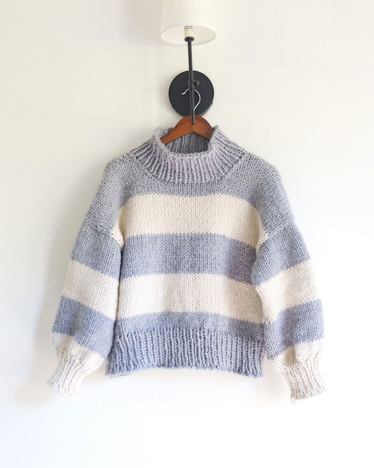 a blue and white striped sweater hanging on a wall next to a wooden hanger