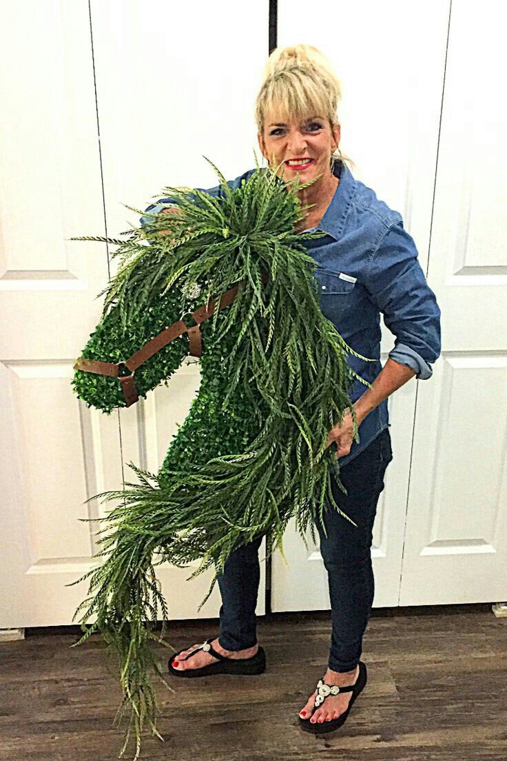 a woman is holding a bunch of green plants