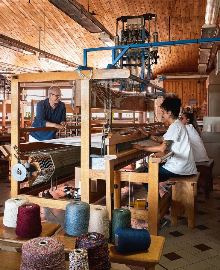 two people working on an old weaving machine