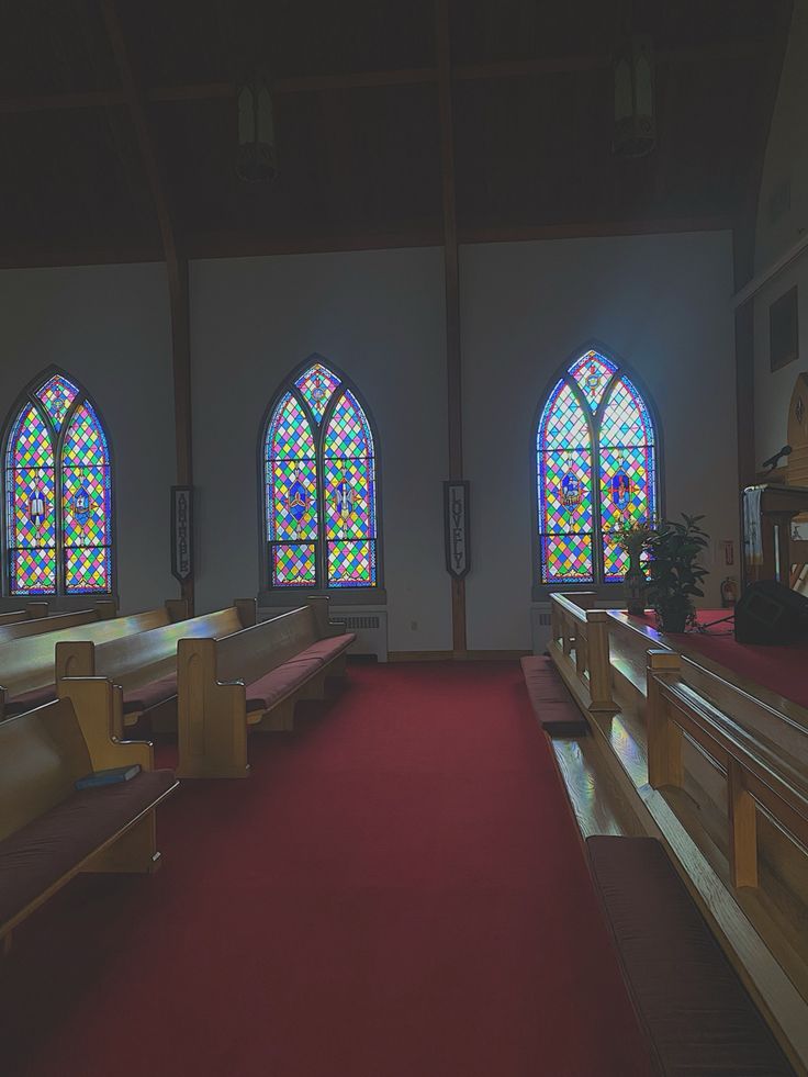 an empty church with stained glass windows and pews