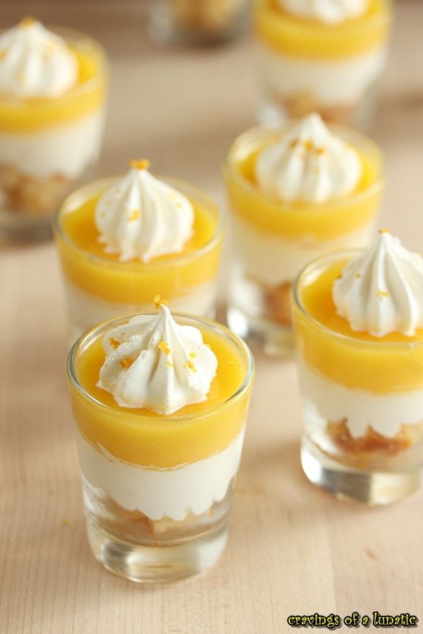 small desserts with whipped cream and orange sauce in glass cups on wooden table top