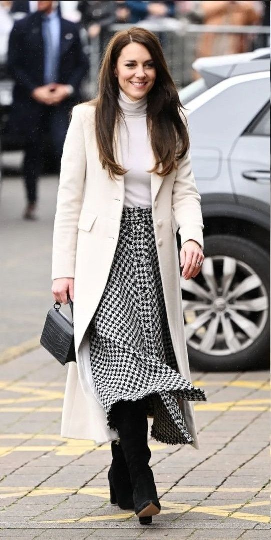 a woman walking down the street in a skirt and coat