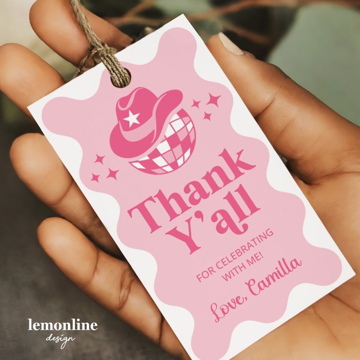 a hand holding a pink thank you card with a hat on it's tag