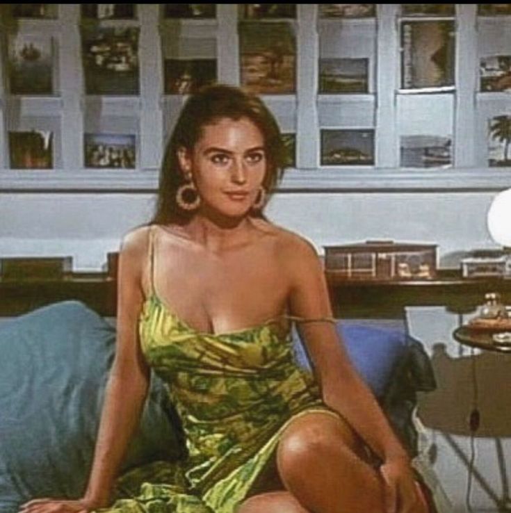 a woman sitting on top of a bed in a green dress