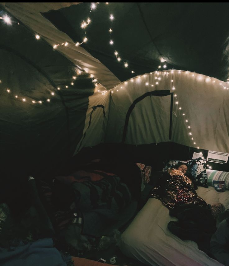 a man is sleeping in a tent with lights on the ceiling