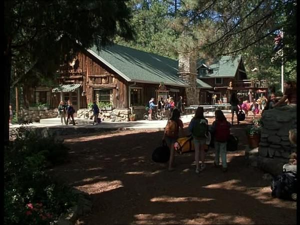 people are walking around in front of a log cabin