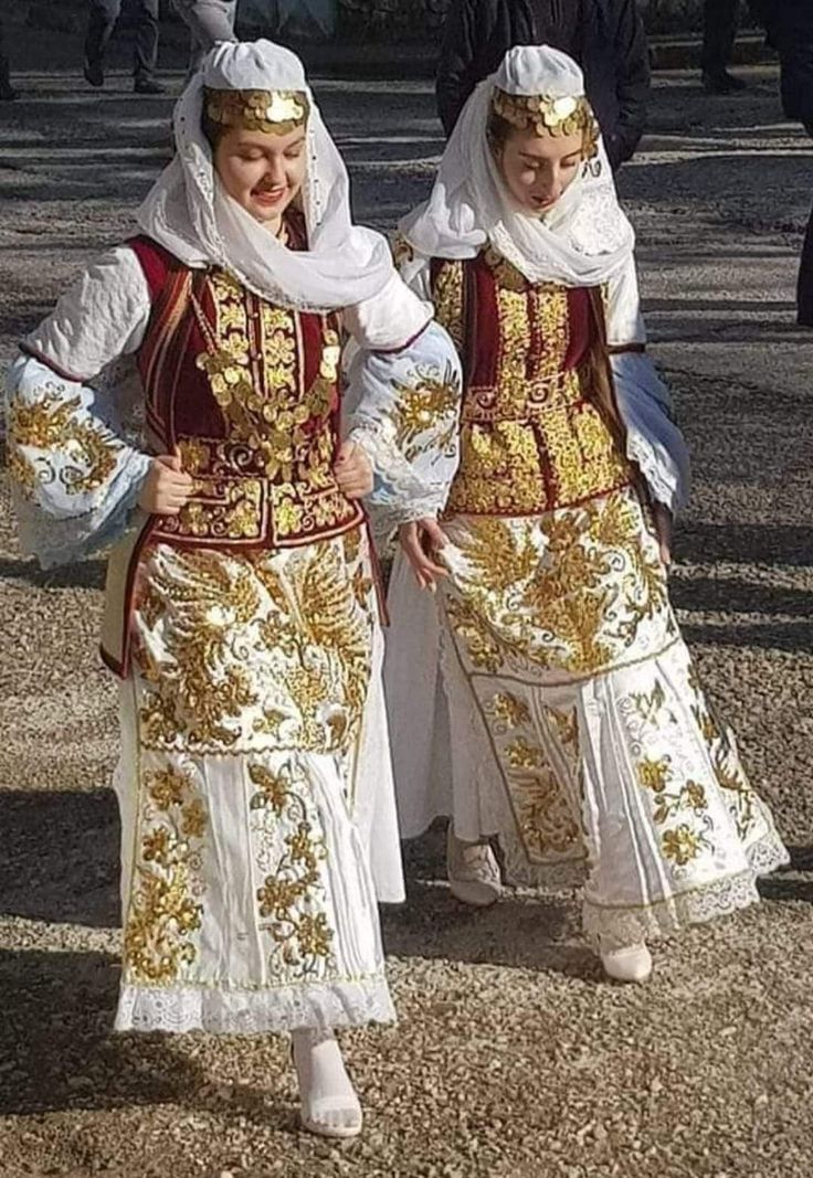 two women dressed in traditional russian clothing walking down the street with their arms around each other