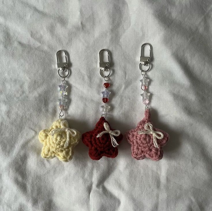 three small crocheted teddy bears are on a white sheet and one is hanging from a clip