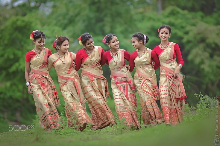 a group of women standing next to each other on top of a lush green field