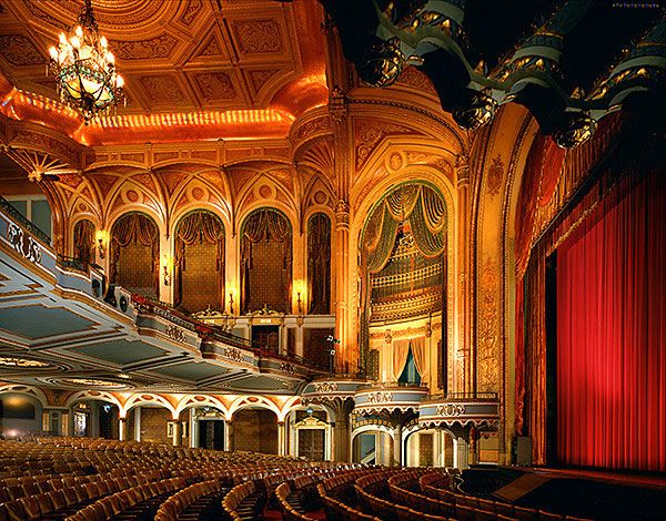 an empty auditorium with red curtains and chandeliers