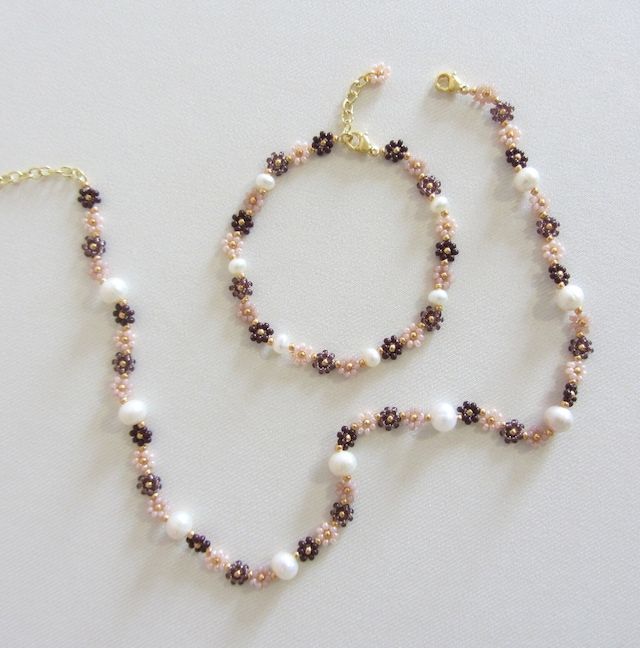 two bracelets with pearls and beads on a white surface, next to each other